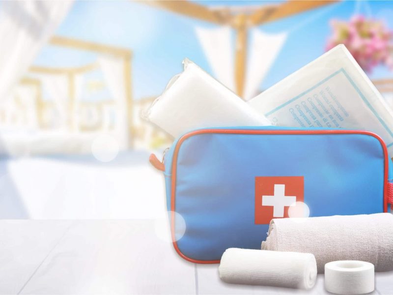 First aid kit with medical supplies on wooden background
