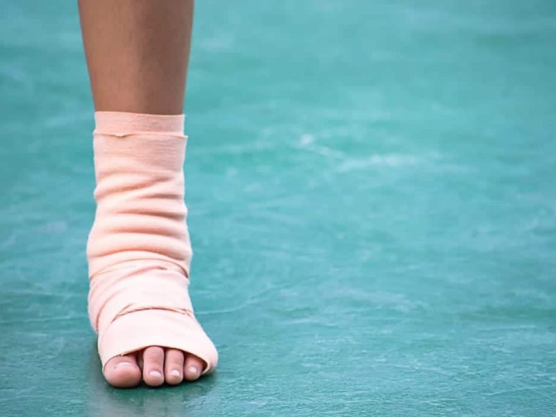the-gauze-bandages-around-the-ankle-boy-and-leg-swelling-from-inflammation-on-a-green-background_t20_E40BwJ